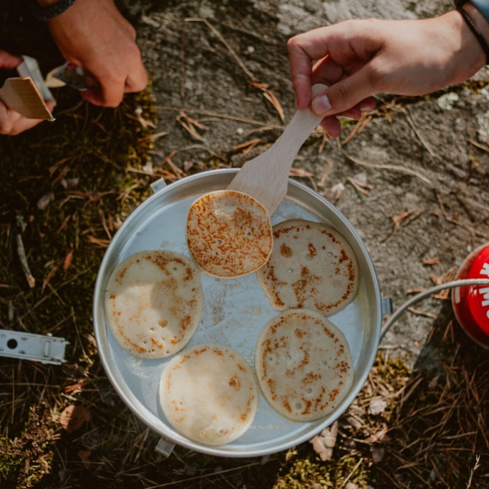 Pancakes frying on a Trangia stove outdoors during a camping trip.