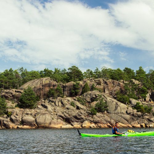 Small kayak with a scenic backdrop of a tall, rocky island.