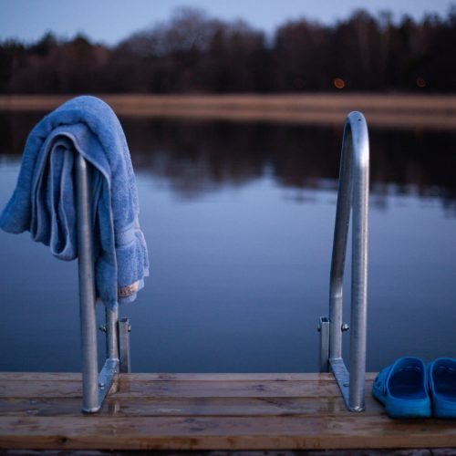 Pier, flip-flops, and towel with water in the background in Vaxholm, Stockholm Archipelago