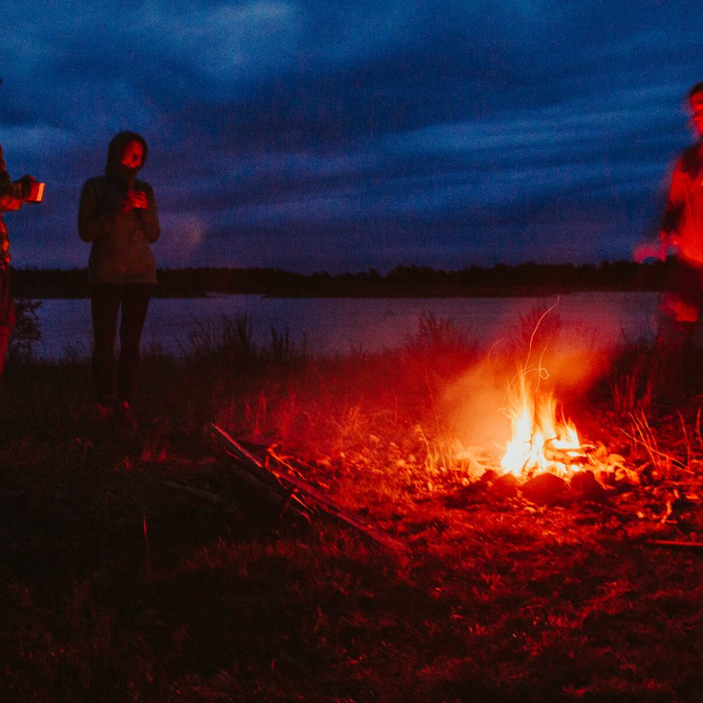 Friends gathered around a campfire after a day of canoeing in Bogesund Nature Reserve.